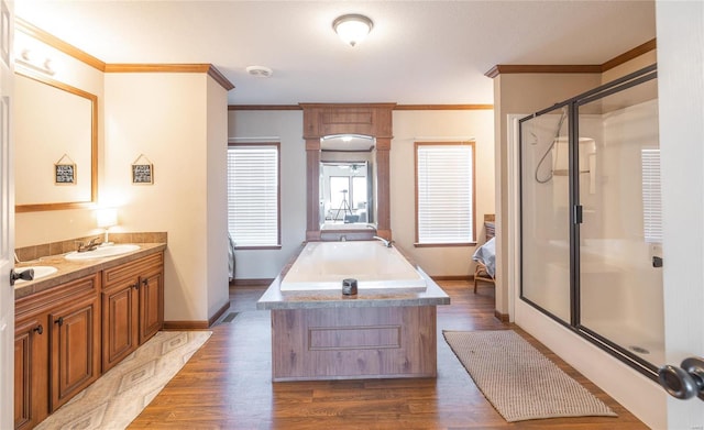 full bathroom featuring a shower stall, vanity, crown molding, wood finished floors, and a garden tub