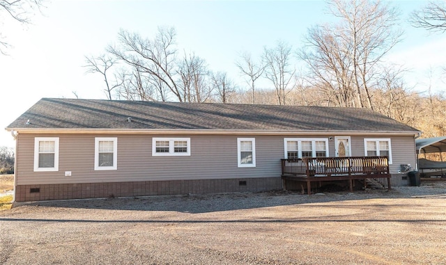 rear view of property with crawl space, a deck, and a shingled roof