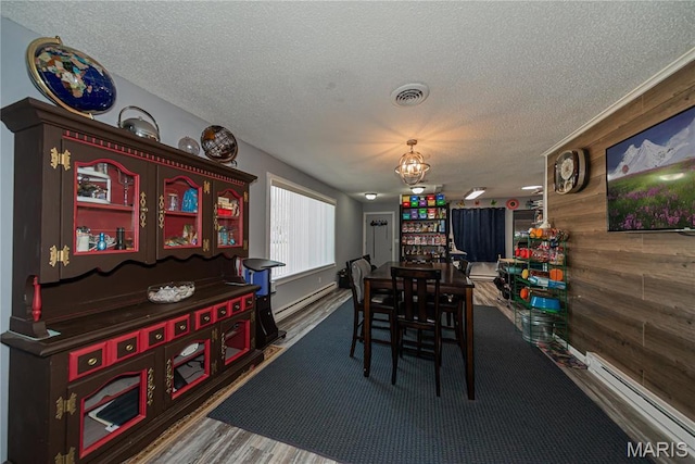 708 E Candy Cane Ln, West Frankfort, IL 62896 - dining room featuring a baseboard heating unit, a textured ceiling, a chandelier, baseboard heating, and wood walls