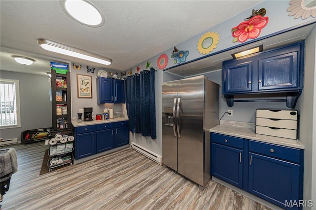 708 E Candy Cane Ln, West Frankfort, IL 62896 - kitchen featuring blue cabinetry, a baseboard heating unit, stainless steel fridge, a textured ceiling, and light countertops