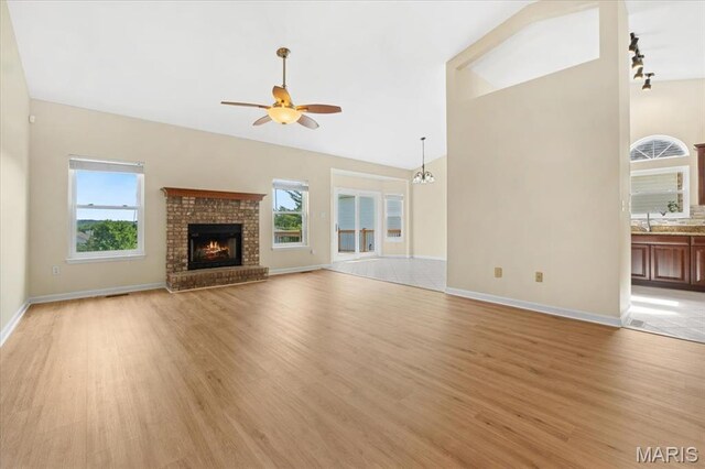 13374 Wintergreen Estates Dr, Fenton, MO 63026 - unfurnished living room featuring a ceiling fan, light wood finished floors, high vaulted ceiling, and a fireplace