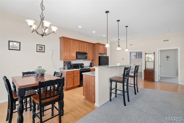 152 Geneva Cove Dr, Innsbrook, MO 63390 - kitchen featuring black appliances, light countertops, a kitchen island, a breakfast bar, and a chandelier