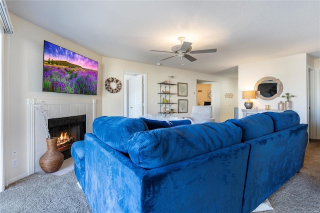 living room featuring carpet flooring, a tiled fireplace, and a ceiling fan