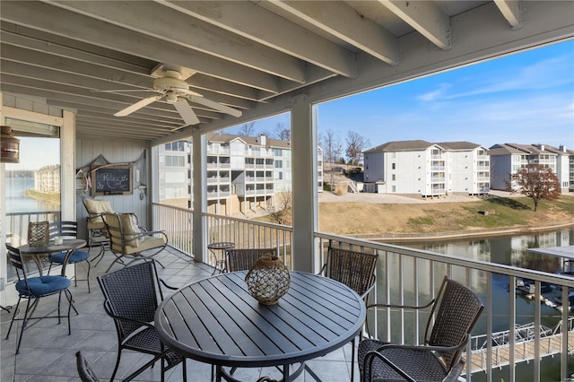 balcony with a water view, ceiling fan, and outdoor dining space