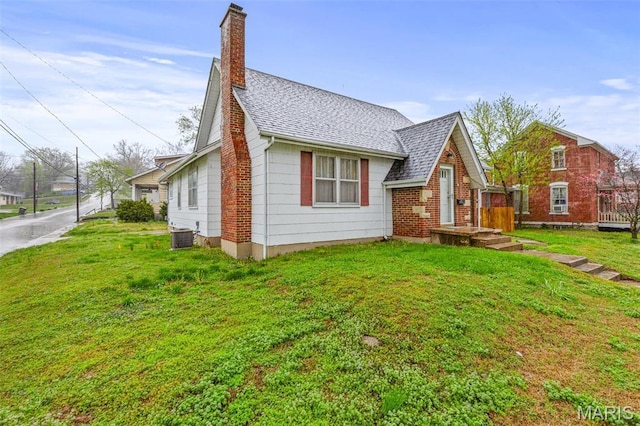 399 Roberts St, Saint Genevieve, MO 63670 - view of front facade featuring a chimney, a shingled roof, a front lawn, and central AC