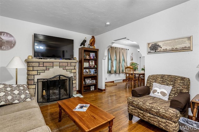 399 Roberts St, Saint Genevieve, MO 63670 - living room with arched walkways, a fireplace, wood finished floors, and a textured ceiling