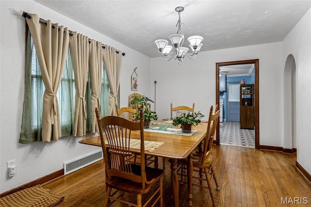 399 Roberts St, Saint Genevieve, MO 63670 - dining room featuring arched walkways, a chandelier, wood finished floors, baseboards, and a textured ceiling