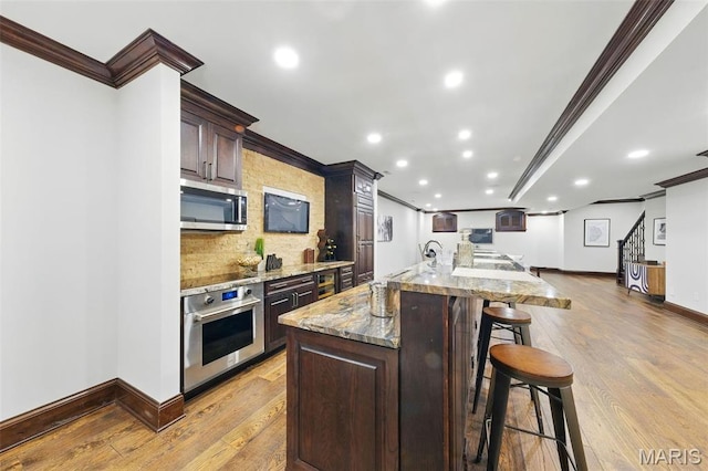 1212 Dolman St, Saint Louis, MO 63104 - kitchen featuring appliances with stainless steel finishes, ornamental molding, backsplash, a spacious island, and light wood-type flooring