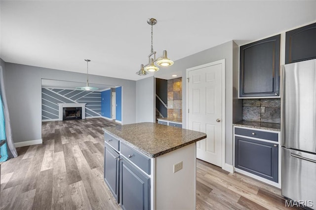 1008 Baypointe Dr, Imperial, MO 63052 - kitchen featuring freestanding refrigerator, light wood-style floors, a fireplace, a center island, and tasteful backsplash