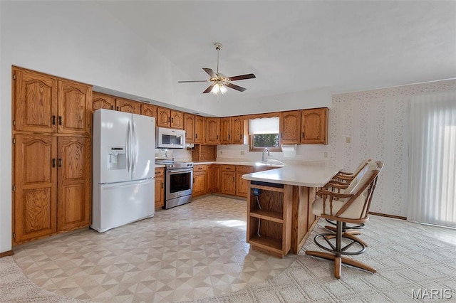 413 Huber Rd, Perryville, MO 63775 - kitchen featuring white appliances, brown cabinetry, a peninsula, ceiling fan, and light countertops