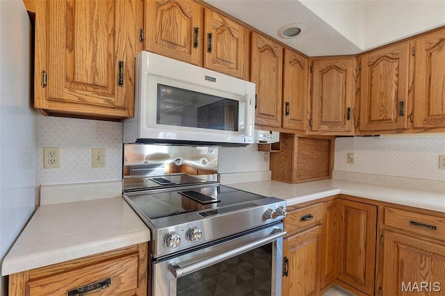 413 Huber Rd, Perryville, MO 63775 - kitchen with white microwave, high end stainless steel range, brown cabinets, light countertops, and tasteful backsplash