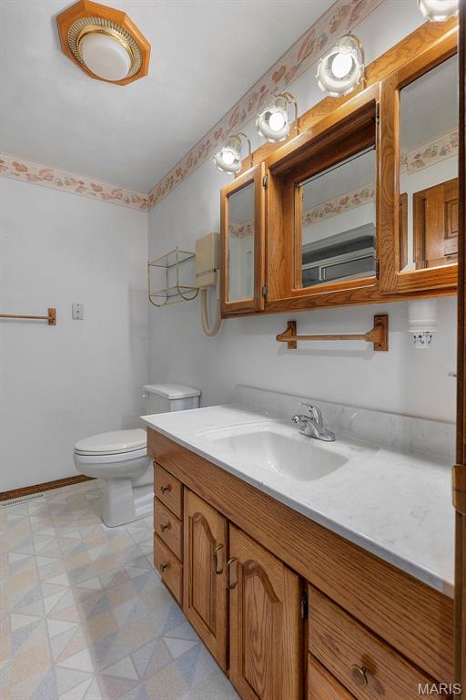 413 Huber Rd, Perryville, MO 63775 - half bathroom featuring tile patterned floors, toilet, vanity, and baseboards