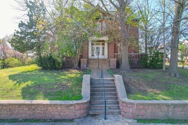 view of front of house featuring a front lawn, brick siding, and stairway
