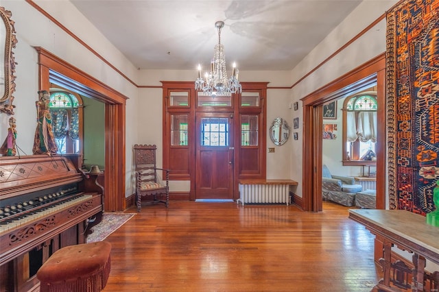 entrance foyer featuring radiator, a chandelier, wood-type flooring, and baseboards