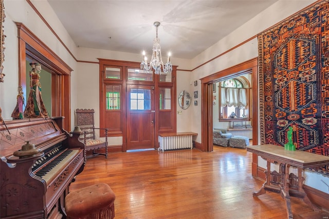 entryway featuring radiator heating unit, a chandelier, wood finished floors, and plenty of natural light
