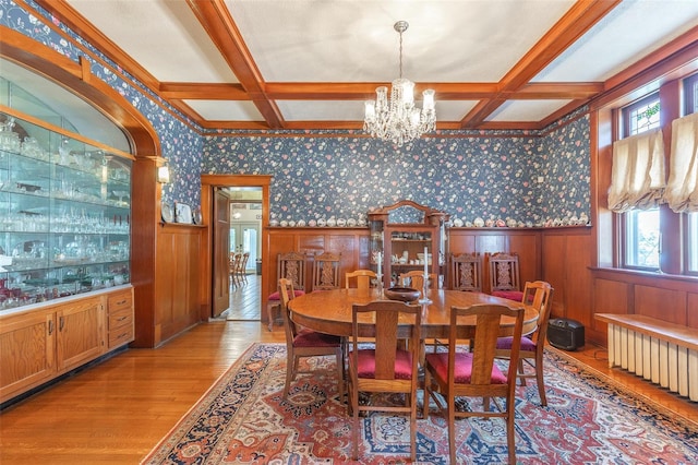 dining room with radiator, light wood-type flooring, wallpapered walls, a chandelier, and coffered ceiling