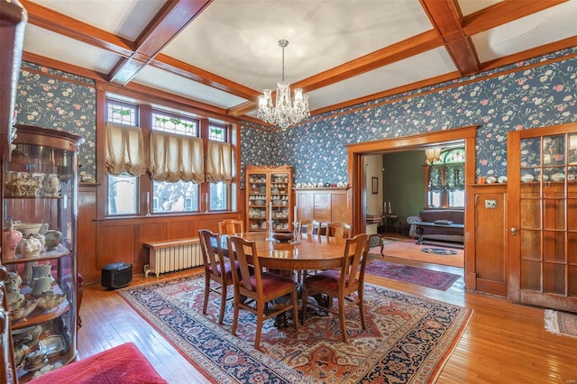 dining area with coffered ceiling, radiator, hardwood / wood-style floors, beamed ceiling, and a wainscoted wall