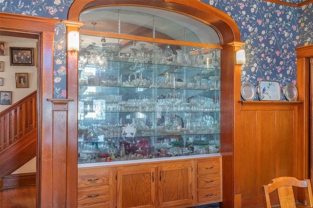 bar area featuring wallpapered walls and stairs