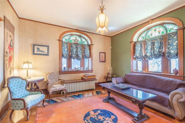 sitting room with healthy amount of natural light, wood finished floors, ornamental molding, and baseboards