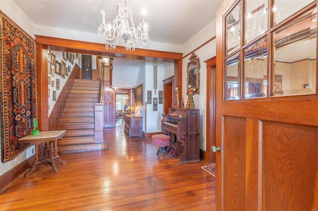 entrance foyer with a chandelier, wood finished floors, stairs, and baseboards