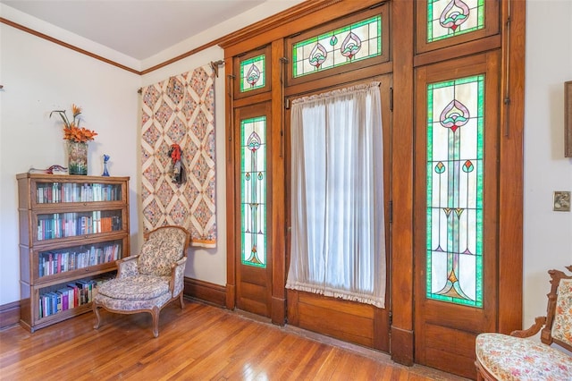 entryway featuring wood finished floors, crown molding, and baseboards