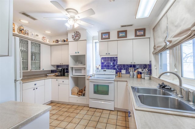 kitchen featuring white appliances, a sink, light countertops, decorative backsplash, and a ceiling fan