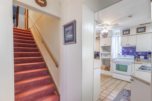 stairway with ceiling fan and tile patterned floors