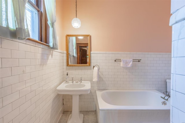 bathroom with tile walls, a bathtub, wainscoting, and tile patterned flooring