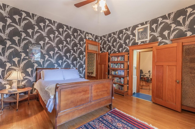 bedroom featuring wallpapered walls, wood finished floors, and ceiling fan