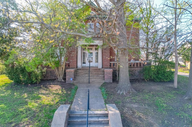 view of front of home featuring french doors, brick siding, and stairway