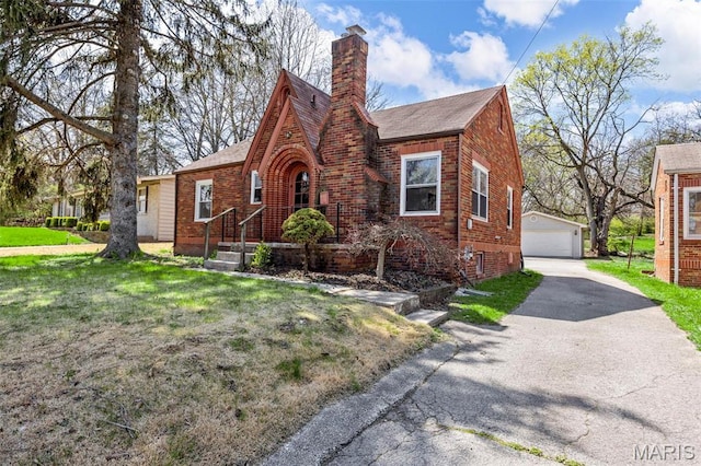 1825 S New Florissant Rd, Florissant, MO 63031 - tudor-style house with an outbuilding, a chimney, a detached garage, a front yard, and brick siding