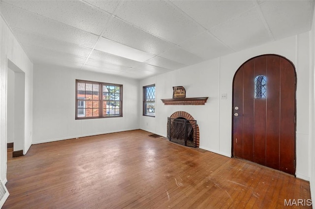 1825 S New Florissant Rd, Florissant, MO 63031 - unfurnished living room with hardwood / wood-style flooring, a brick fireplace, a drop ceiling, and baseboards
