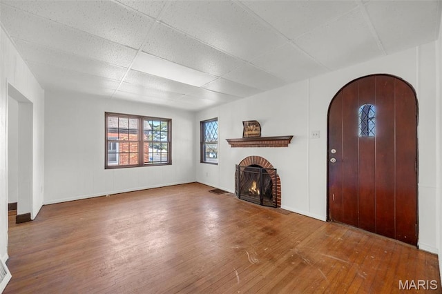 1825 S New Florissant Rd, Florissant, MO 63031 - unfurnished living room featuring hardwood / wood-style floors, a fireplace, baseboards, a drop ceiling, and arched walkways
