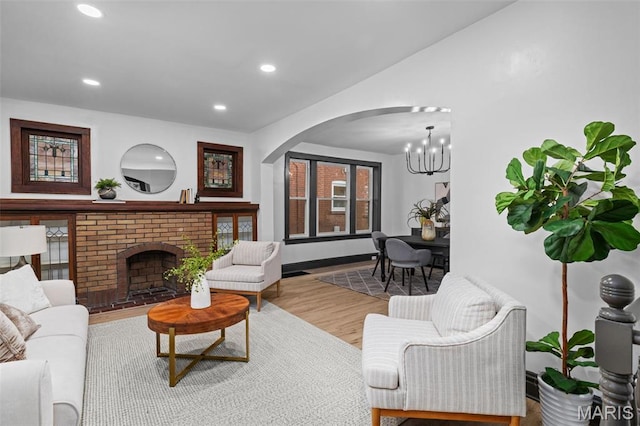 6007 S Kingshighway Blvd S, Saint Louis, MO 63109 - living room featuring a chandelier, arched walkways, recessed lighting, wood finished floors, and a brick fireplace