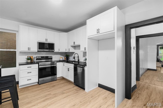 6007 S Kingshighway Blvd S, Saint Louis, MO 63109 - kitchen with appliances with stainless steel finishes, a sink, dark countertops, and light wood-style floors
