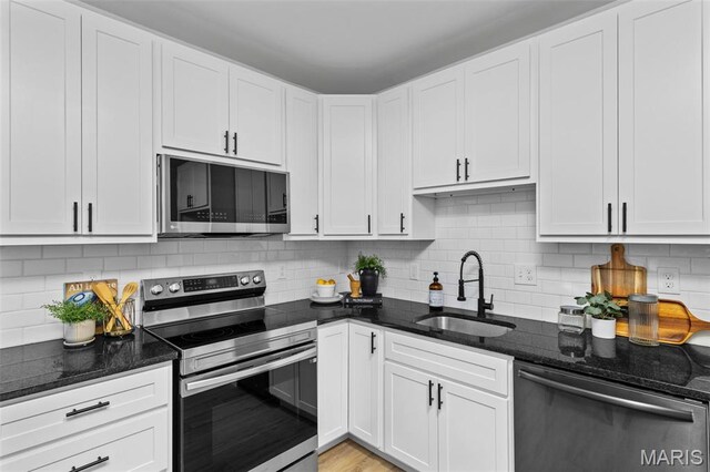 6007 S Kingshighway Blvd S, Saint Louis, MO 63109 - kitchen featuring appliances with stainless steel finishes, a sink, dark stone countertops, backsplash, and white cabinets
