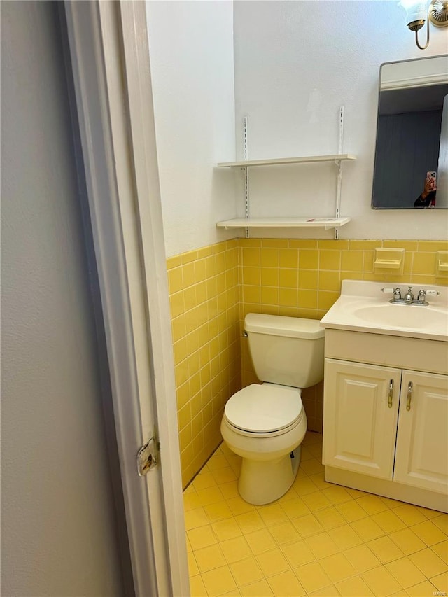 4400 Mohegan Dr, Saint Louis, MO 63123 - half bath with tile patterned flooring, toilet, vanity, tile walls, and a wainscoted wall
