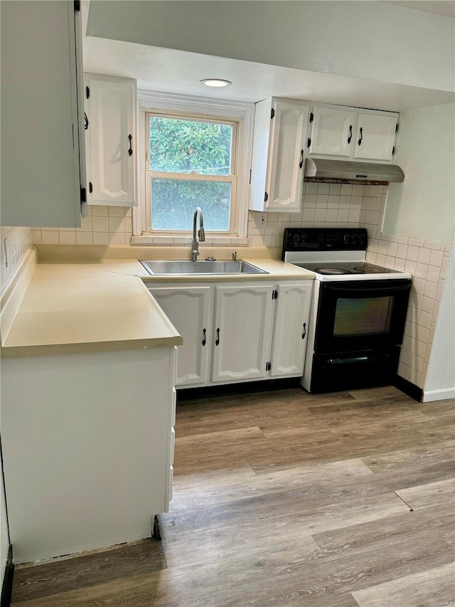 4400 Mohegan Dr, Saint Louis, MO 63123 - kitchen with electric stove, a sink, under cabinet range hood, and wood finished floors