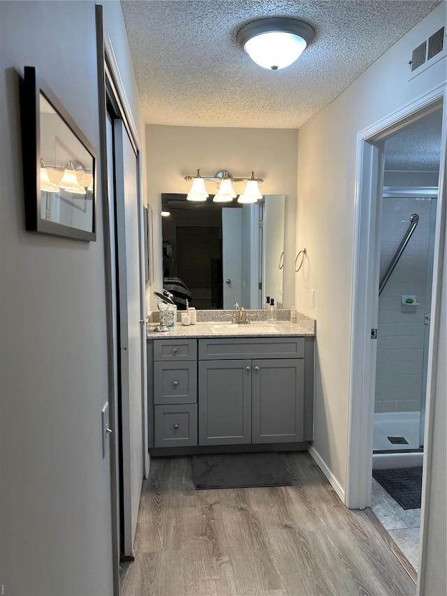 572 Coeur De Royale Unit 103, Creve Coeur, MO 63141 - full bath with a textured ceiling, a stall shower, vanity, and wood finished floors
