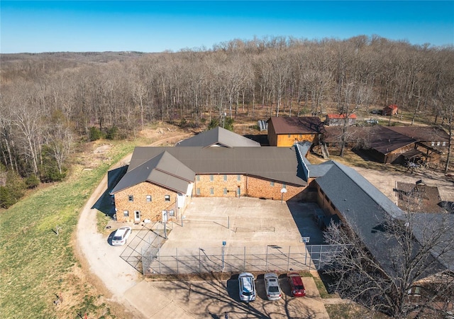 aerial view of property and surrounding area featuring a heavily wooded area