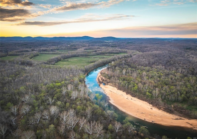 aerial view at dusk of a wooded view and a water and mountain view