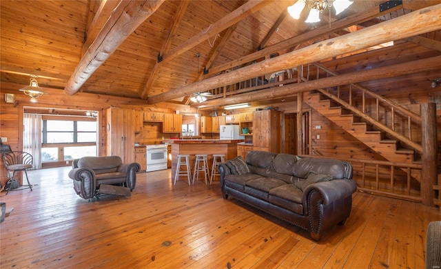 living room featuring wooden walls, light wood-style floors, beam ceiling, wooden ceiling, and a ceiling fan