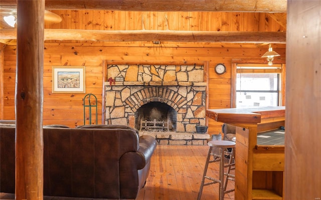 living area with wooden walls, hardwood / wood-style floors, and a stone fireplace