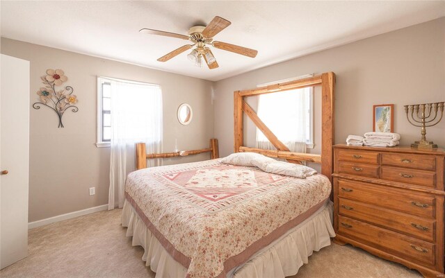 bedroom featuring light carpet, a ceiling fan, and baseboards