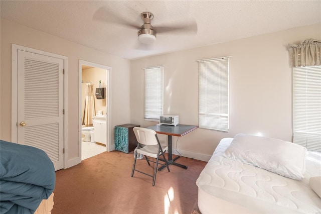 bedroom with carpet, baseboards, ensuite bathroom, and ceiling fan