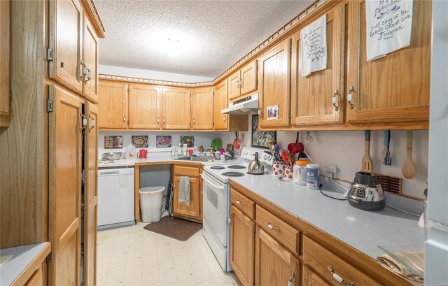 kitchen with white appliances, under cabinet range hood, light countertops, a textured ceiling, and a sink