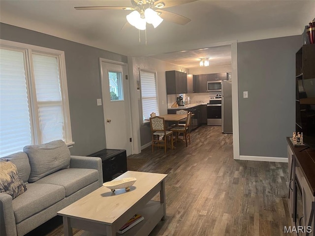 living area with ceiling fan, dark wood-type flooring, and baseboards