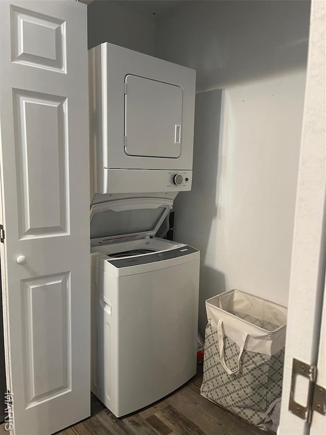 laundry room with estacked washer and dryer and dark wood-type flooring