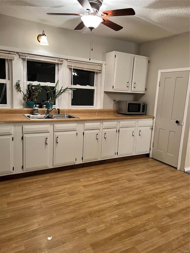 108 Rau St, Waterloo, IL 62298 - kitchen featuring stainless steel microwave, a sink, white cabinets, a ceiling fan, and light wood-type flooring