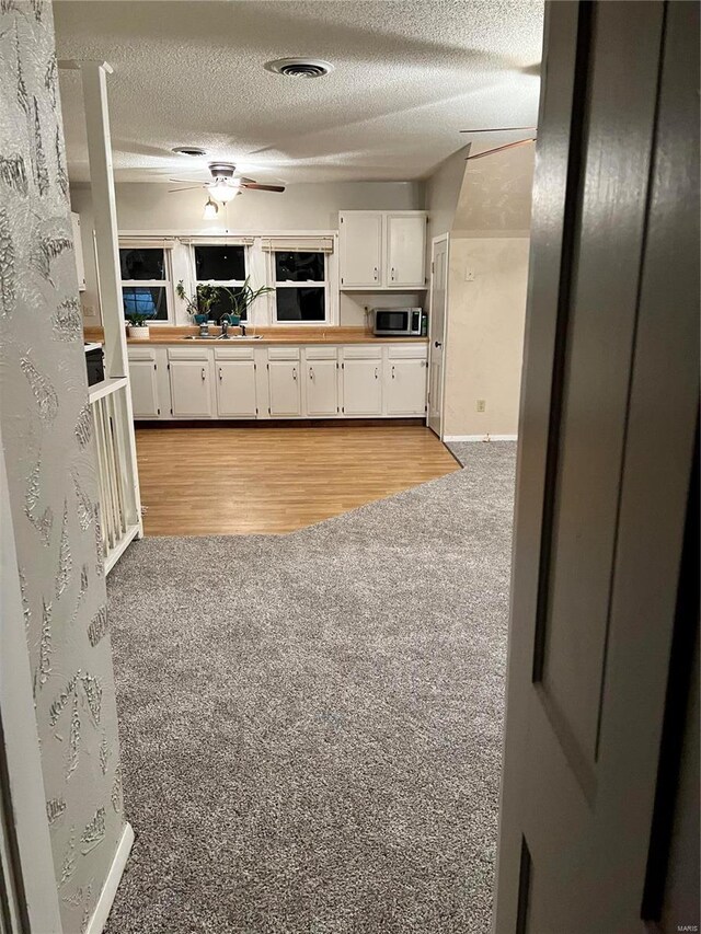 108 Rau St, Waterloo, IL 62298 - kitchen featuring light colored carpet, stainless steel microwave, white cabinets, a textured ceiling, and baseboards